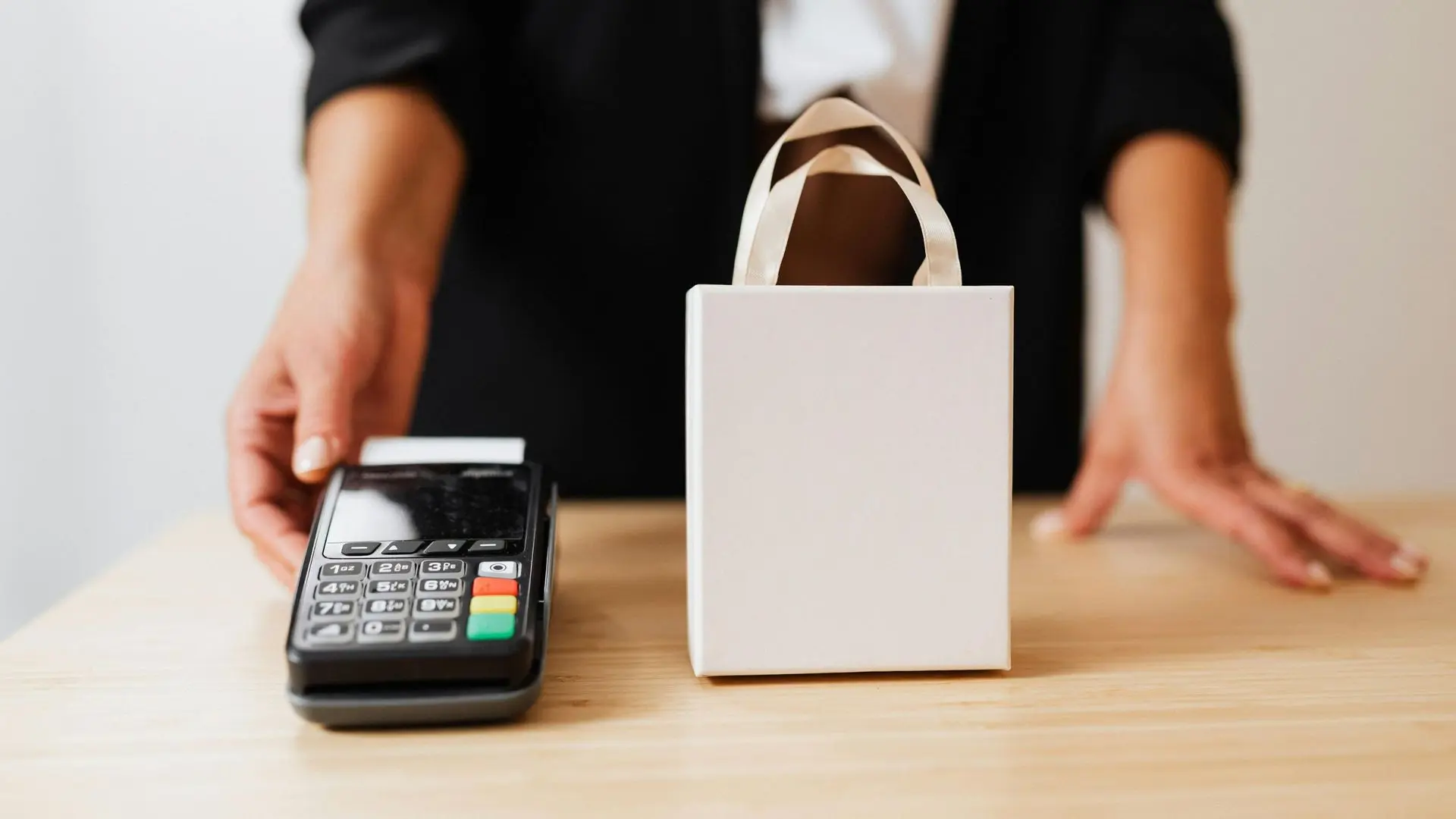 Commerçante devant un TPE et un sac de commande, illustrant la gestion flexible des comptes praticiens à distance sans changement de matériel