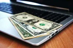 Billets de dollars posés sur un ordinateur portable, symbolisant la collecte de dons sans commission via Payludd