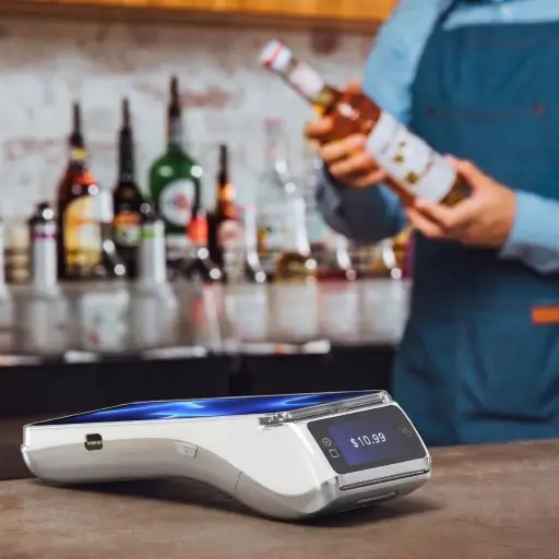 Cette image, mettant en scène un serveur dans un bar, illustre parfaitement la force du PAX A920 Pro ICONIC : sa mobilité. En tant que solution mobile complète, il est l'outil idéal pour de nombreux secteurs d'activité. Dans la restauration et l'hôtellerie, il permet l'encaissement à table, la gestion des pourboires et des titres-restaurant en toute fluidité. Pour le commerce de détail, il se transforme en caisse mobile lors des pics d'affluence, permet le paiement en rayon et facilite la gestion des stocks grâce à son scanner intégré. Enfin, il est indispensable pour les professionnels en déplacement (artisans, livreurs, taxis) qui ont besoin d'encaisser de manière fiable et sécurisée partout, grâce à sa connectivité 4G. Dans chaque cas, le PAX A920 Pro ICONIC est l'outil parfait pour moderniser son service et offrir une expérience client irréprochable.