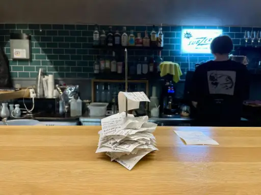 Pile de tickets commerçants en désordre sur comptoir de restaurant illustrant le besoin d'archivage