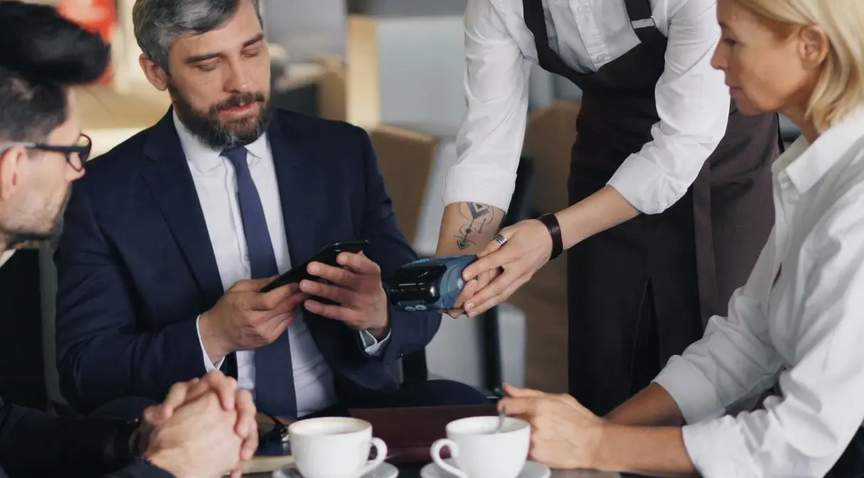 Serveur et clients en restaurant utilisant un terminal de paiement connecté