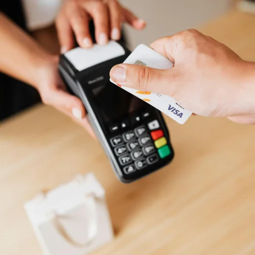 Gros plan sur un client utilisant une carte bancaire avec puce sur un terminal de paiement mobile (TPE) pour finaliser un achat