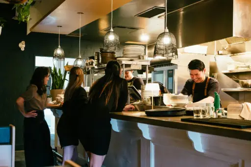 Équipe de restauration au comptoir, heureuse de profiter de la gestion simplifiée des pourboires sur leur TPE grâce à Payludd.