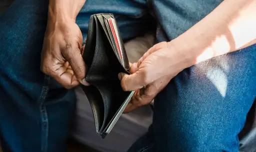 Homme consultant l'intérieur de son portefeuille ouvert.