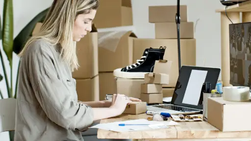 E-commerçante préparant des cartons d'expédition pour les commandes de sa boutique en ligne.