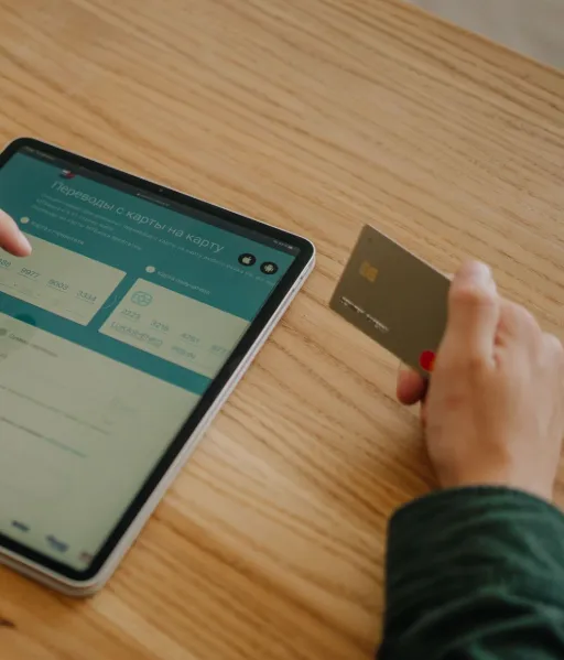 Consultation d'une interface de gestion financière sur une tablette avec une carte de crédit à la main.