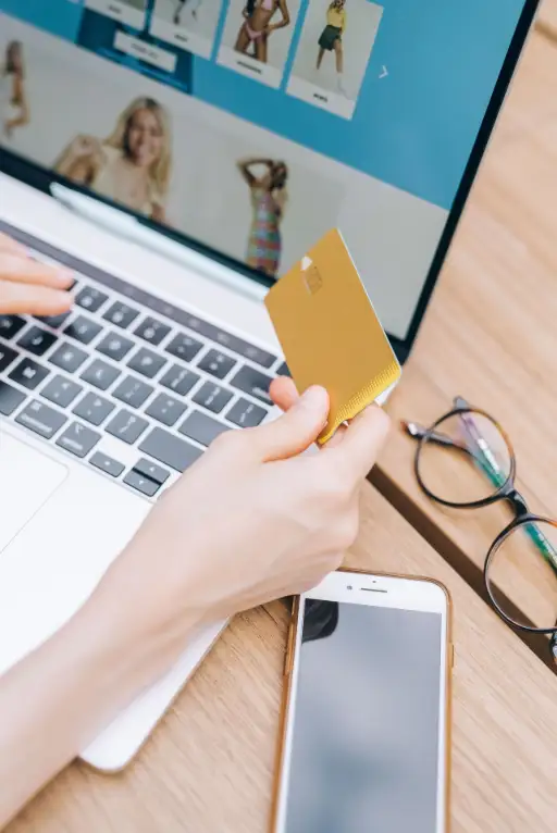 Personne effectuant un achat en ligne avec une carte bancaire sur le clavier d'un ordinateur portable.